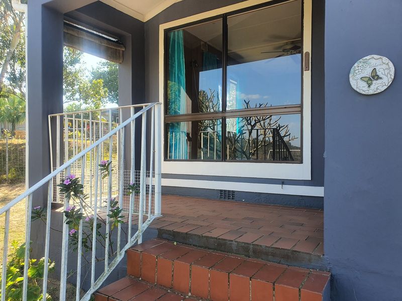 A covered patio entrance featuring terracotta tiled steps, a metal balustrade, and a large sliding glass door providing access to the home.