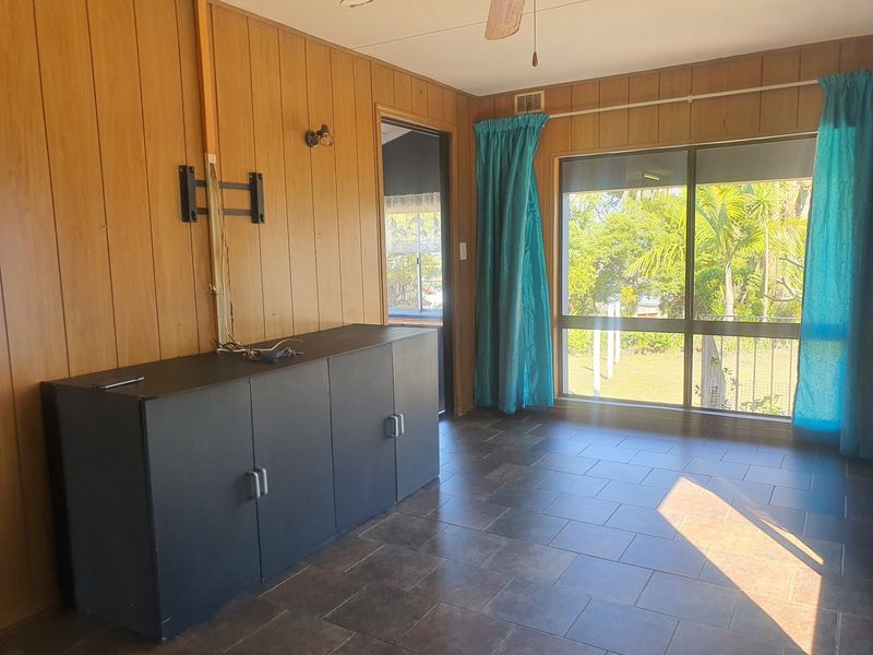 Living room featuring wood paneling, tiled flooring, and a sliding glass door providing access to the outdoor area.