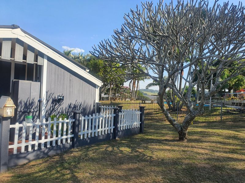 A view of the rear exterior of the townhouse featuring timber cladding, a gabled roof, and a white picket fence bordering the garden area.