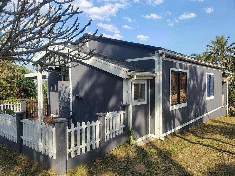 Rear view of the townhouse featuring a covered patio area, white picket fencing, and dark grey exterior cladding with white trim.
