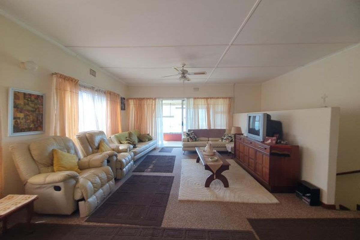 Spacious living room featuring a ceiling fan, partition wall, and carpet flooring, offering a functional layout with potential for modern updates.