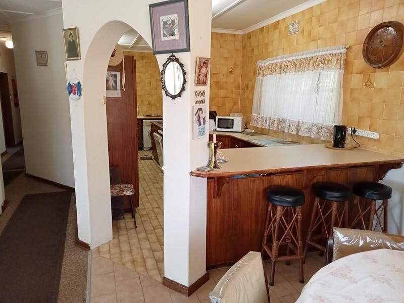 A dated kitchen featuring a breakfast bar, arched entryway, and traditional tiled splashback, offering potential for a modern renovation.