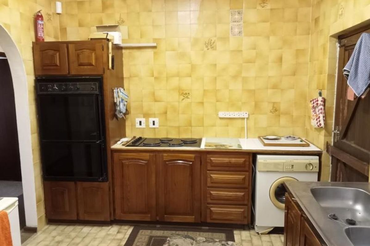 A dated kitchen featuring wooden cabinetry, a built-in oven, electric hob, and tiled wall finishes, offering significant potential for a modern renovation.
