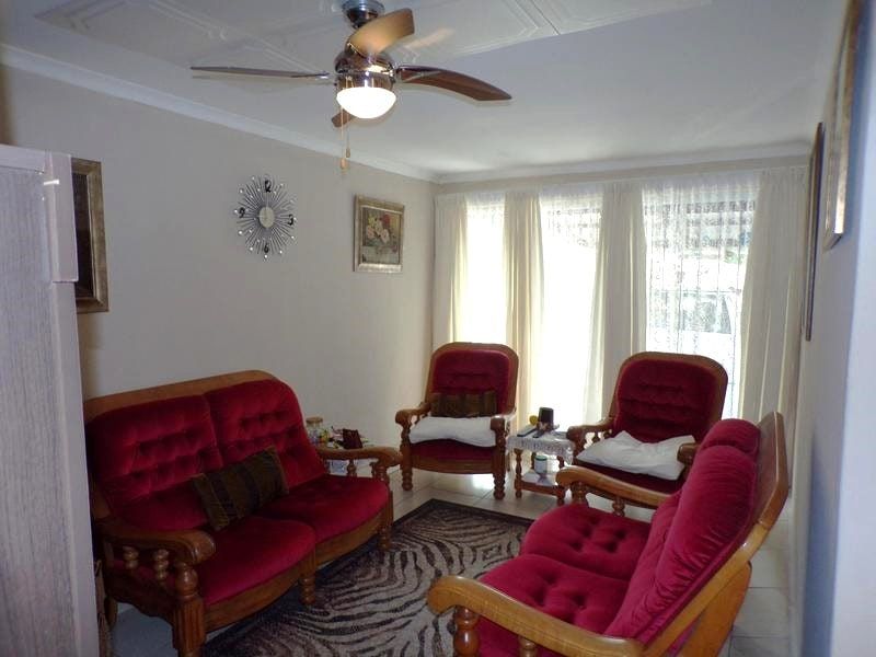 A cozy living room featuring tiled flooring, a ceiling fan, and coved ceiling details, providing a comfortable space for relaxation.