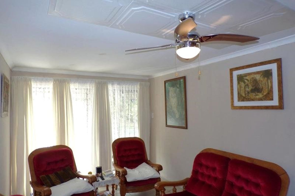 A living room featuring a tiled ceiling, ceiling fan, and tiled flooring with large windows covered by curtains.