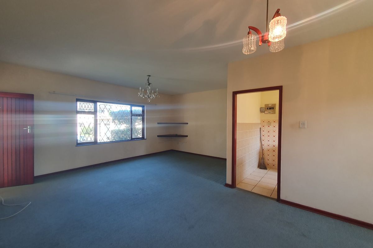 Spacious, empty living area featuring carpet flooring, built-in shelving, and direct access to an adjacent utility space.