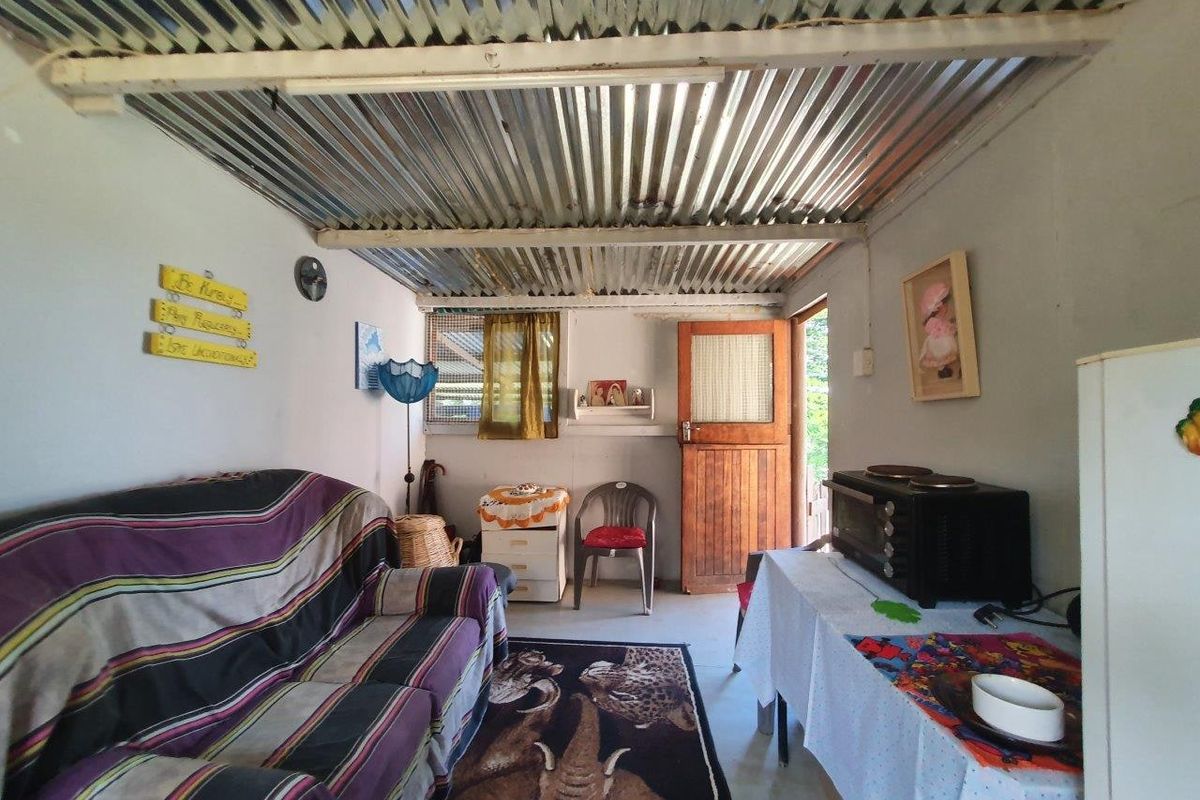 A modest living area featuring a corrugated iron ceiling, timber door, and basic finishes, offering potential for renovation and modernization.