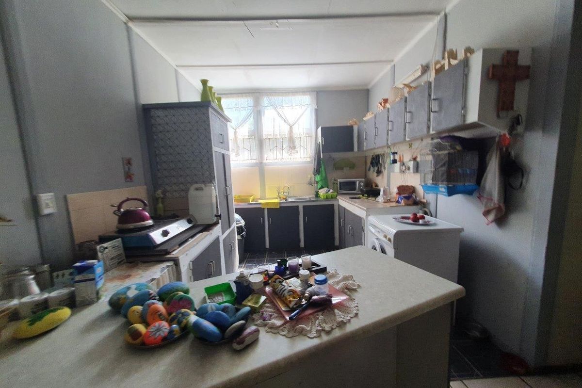 A functional kitchen featuring built-in cabinetry, laminate countertops, and a stainless steel sink, offering potential for modernization and layout optimization.