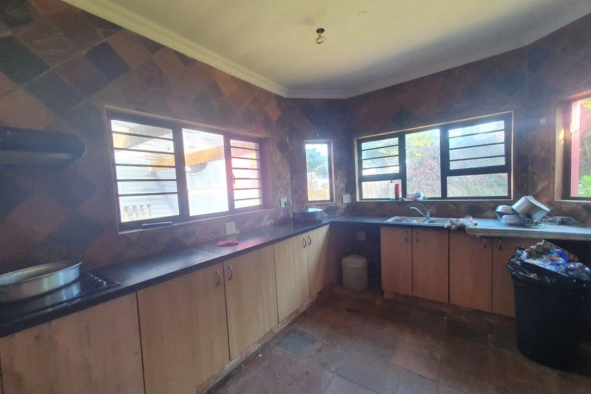 A functional kitchen featuring laminate cabinetry, dark stone countertops, a double bowl sink, and tiled finishes throughout, offering a practical layout for daily use.