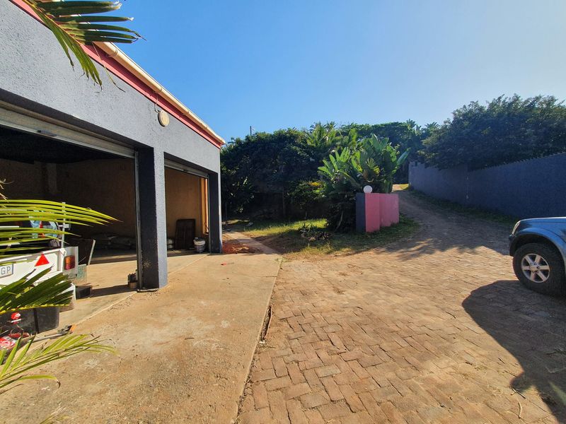A view of a double garage with a paved driveway and surrounding boundary walls, showing potential for exterior maintenance and landscaping improvements.