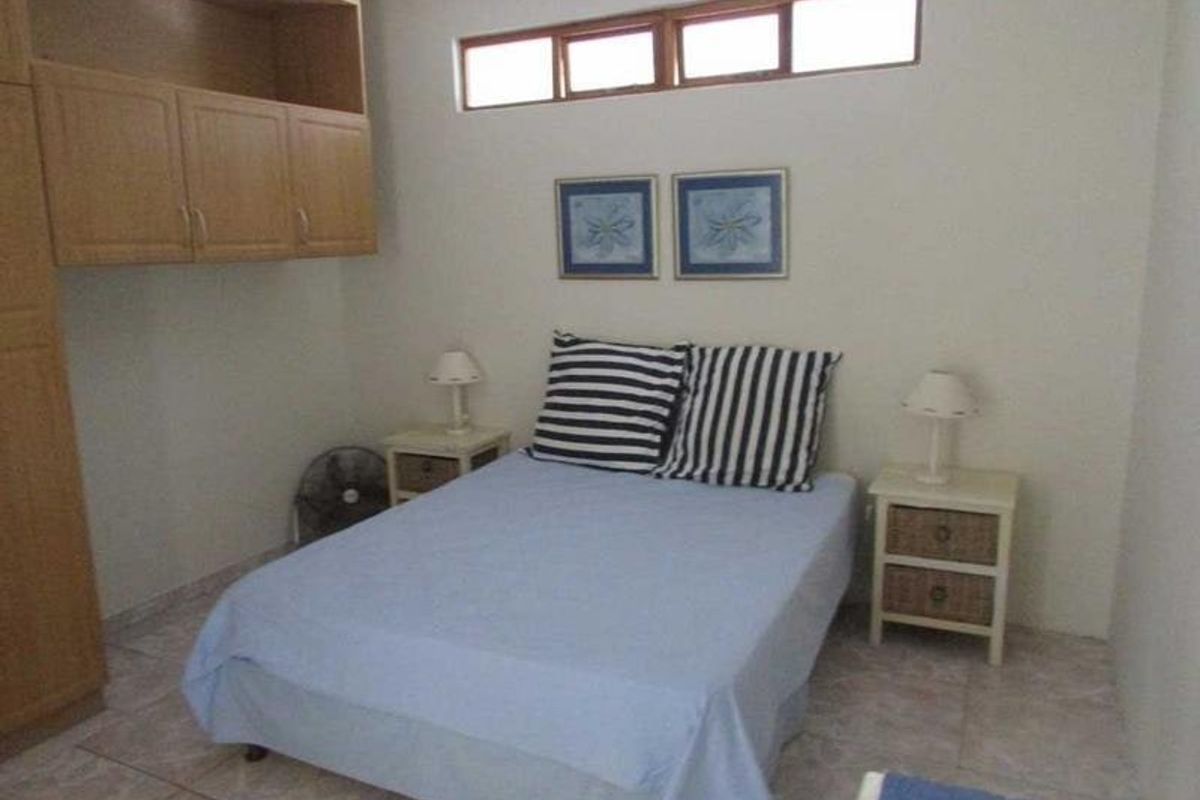 A functional bedroom featuring built-in cabinetry, tiled flooring, and a high-level clerestory window for natural light.