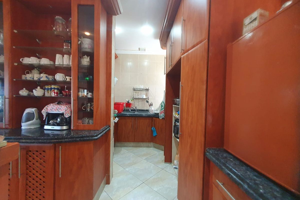 A functional kitchen featuring extensive wooden cabinetry, granite countertops, and a tiled backsplash, offering ample storage and workspace.