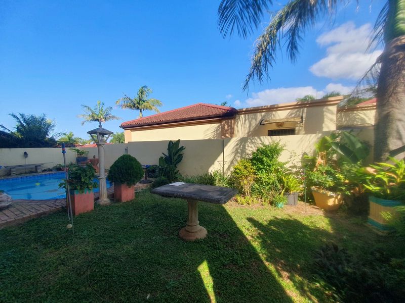 A private outdoor pool area featuring a swimming pool, perimeter wall, and established garden landscaping.