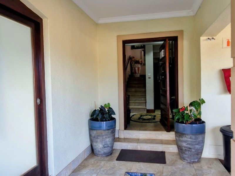 A covered entrance area featuring tiled flooring and a solid wood door frame leading into the interior of the townhouse.