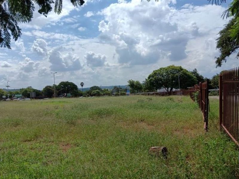 A vacant residential plot featuring open grass land and metal perimeter fencing, suitable for future development.