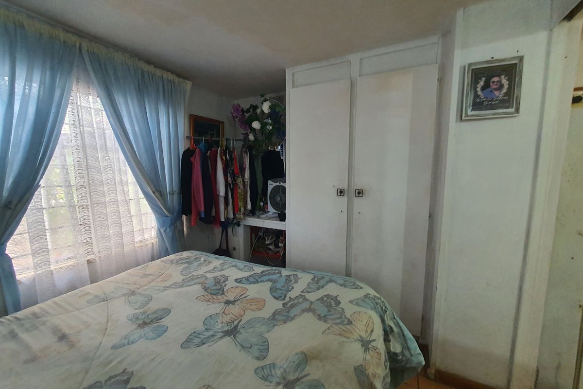 A bedroom featuring built-in cupboards and tiled flooring, requiring some cosmetic updates to improve its overall condition.