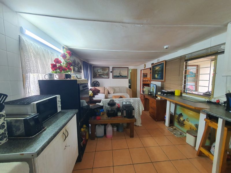 Open-plan living and kitchen area featuring tiled flooring, built-in cabinetry, and functional layout with potential for modernization.