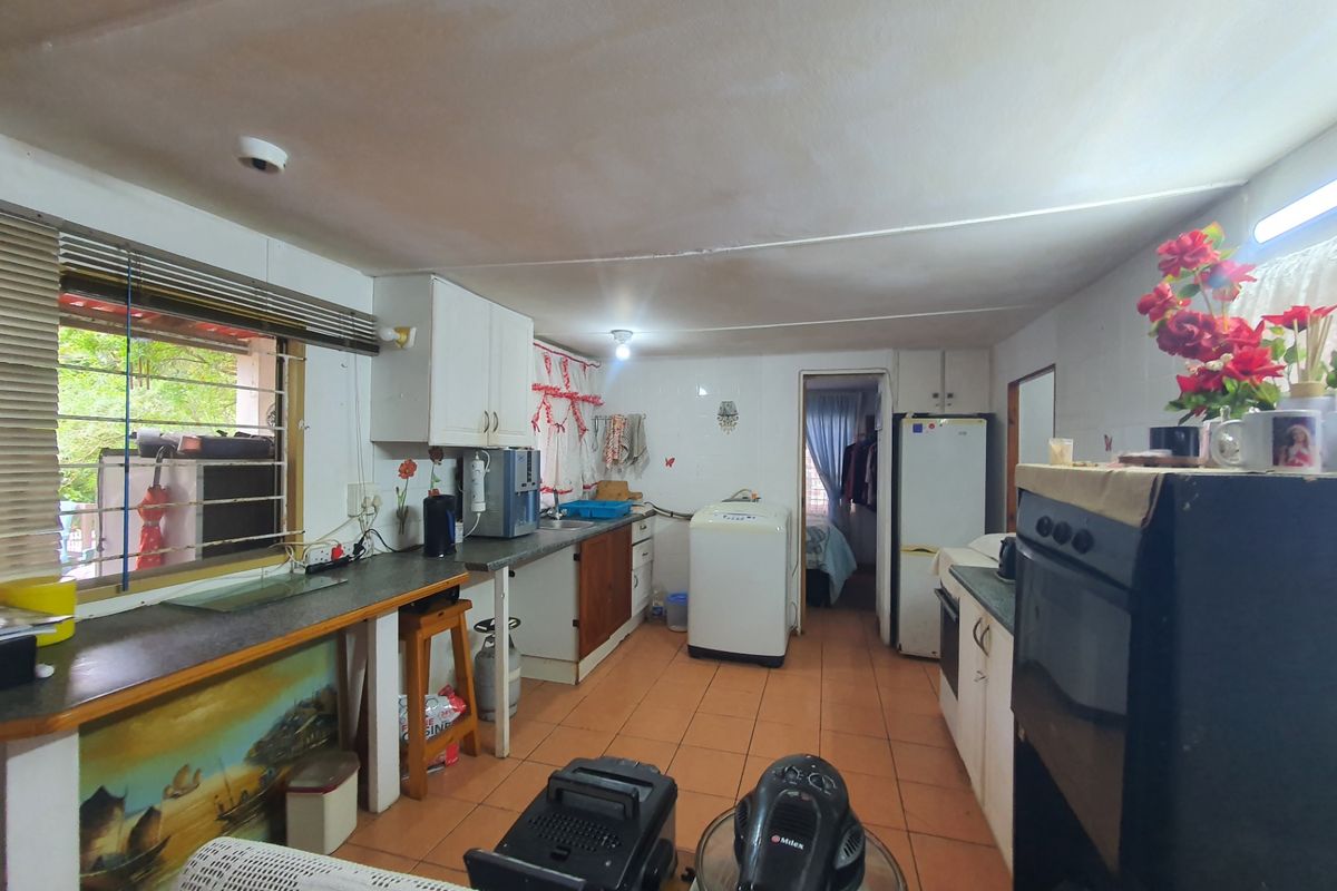 A functional kitchen space featuring tiled flooring, built-in cabinetry, and laminate countertops, offering potential for modernization and layout optimization.