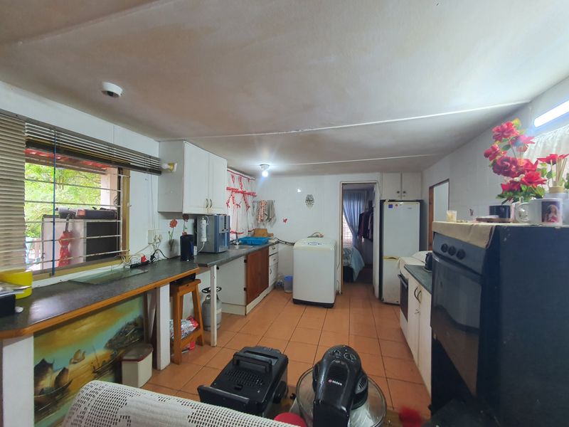 A functional kitchen space featuring tiled flooring, built-in cabinetry, and laminate countertops, offering potential for modernization and layout optimization.