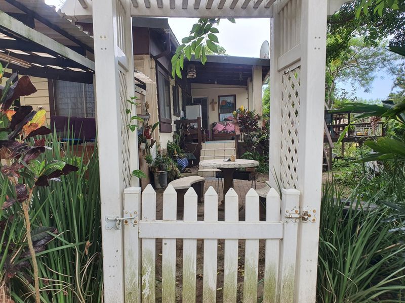 Rear garden area featuring a white timber picket gate, pergola entrance, and paved patio space leading to the main dwelling.