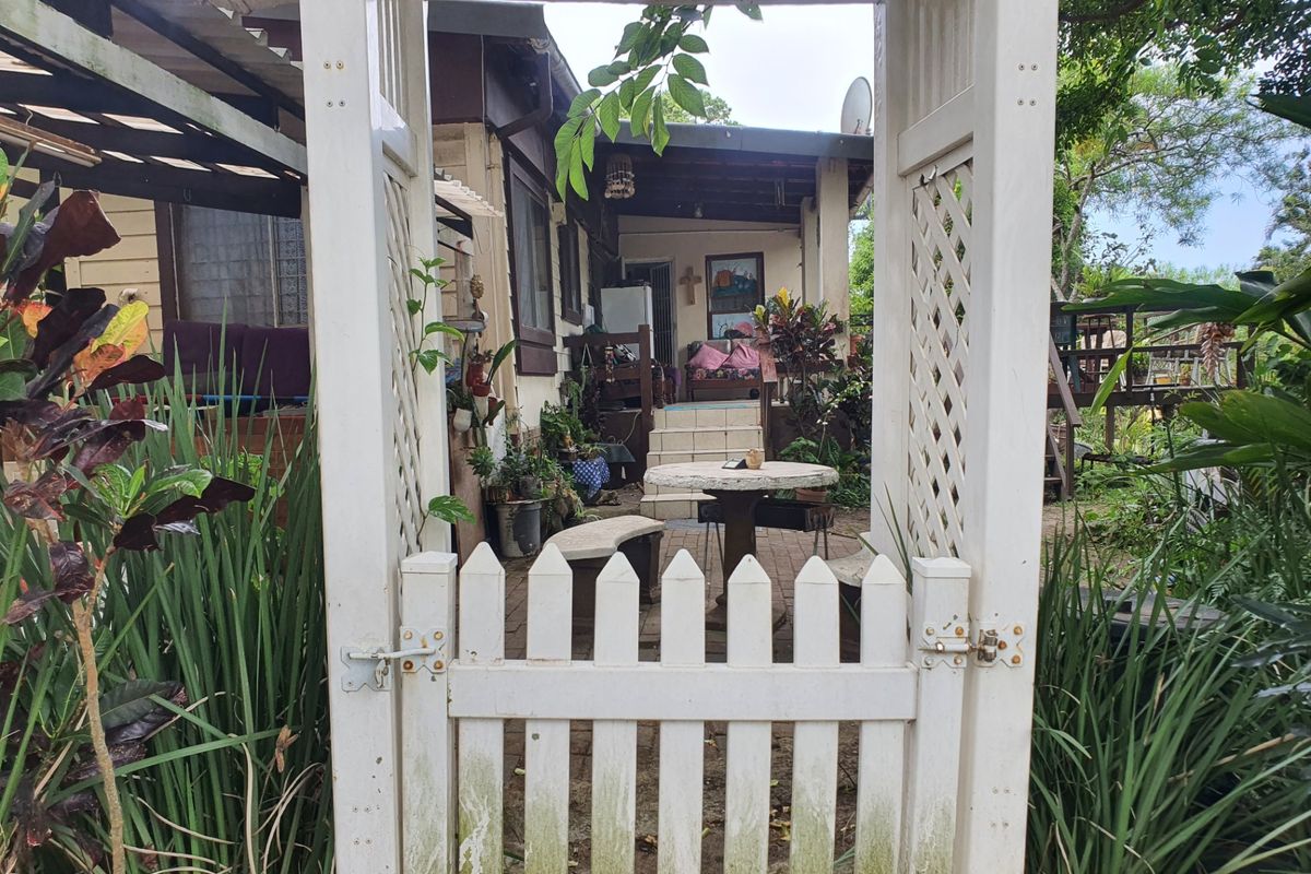 Rear garden area featuring a white timber picket gate, pergola entrance, and paved patio space leading to the main dwelling.