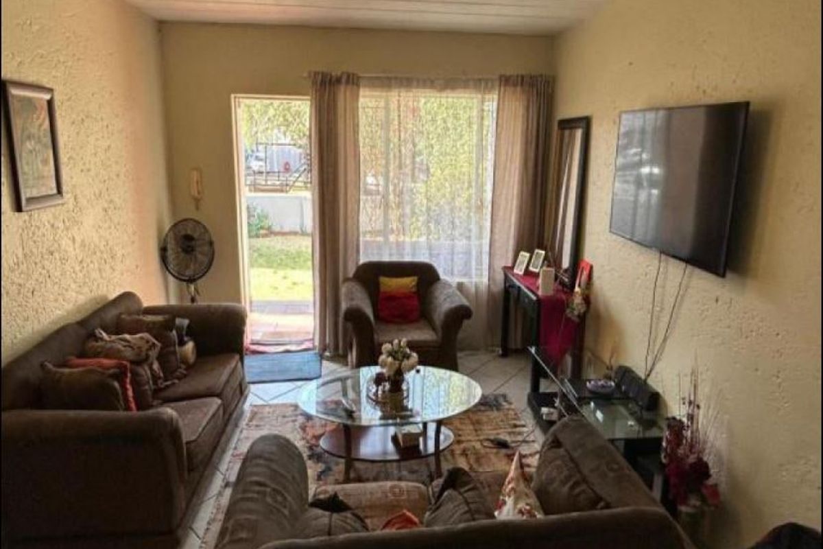 A living room featuring tiled flooring, textured walls, and a sliding glass door providing access to the exterior.