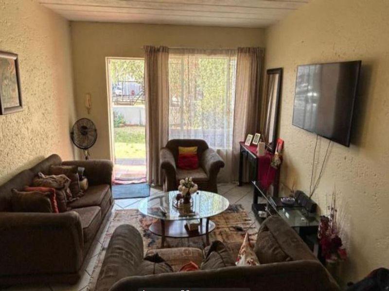 A living room featuring tiled flooring, textured walls, and a sliding glass door providing access to the exterior.