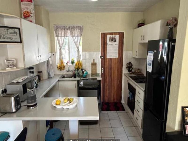 A compact kitchen featuring built-in cabinetry, a tiled backsplash, and integrated cooking appliances, offering a functional layout with potential for cosmetic updates.