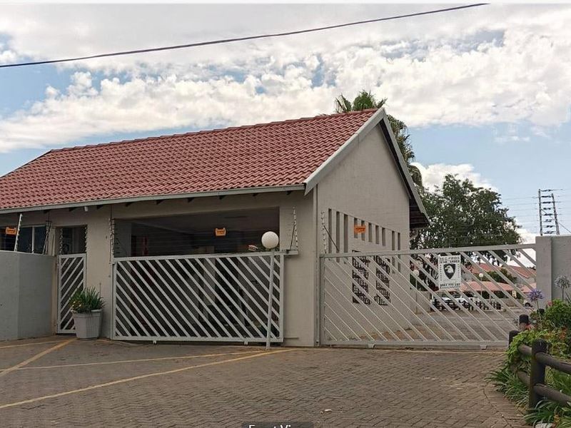 Front exterior view of the property featuring a tiled roof, paved driveway, and secure gated entrance with electric fencing.