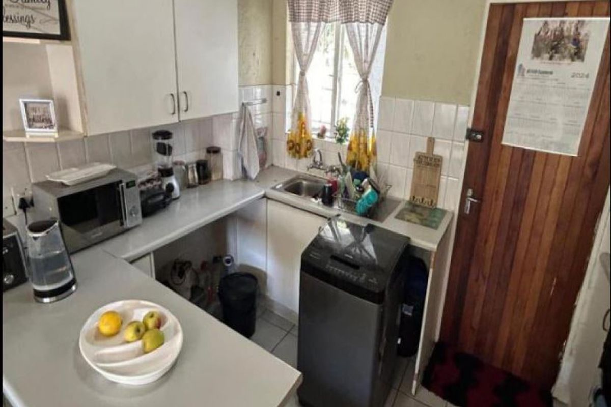 Compact kitchen featuring built-in cabinetry, laminate countertops, and a stainless steel sink, offering a functional layout with direct access to an exterior door.