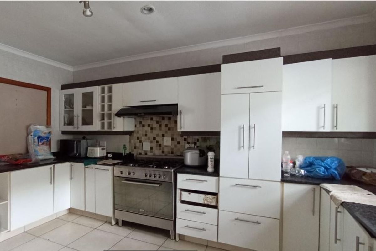 A functional kitchen featuring white cabinetry, a gas stove with extractor fan, mosaic tile backsplash, and tiled flooring.