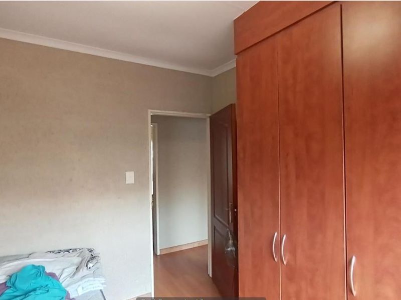 A bedroom featuring laminate flooring and a large built-in wooden wardrobe, providing ample storage space.