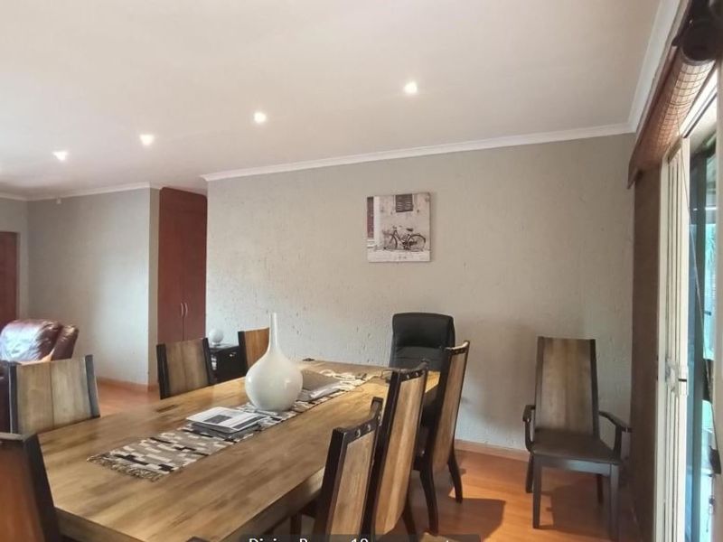 A dining area featuring laminate flooring, recessed downlighting, and a sliding glass door providing access to the exterior.