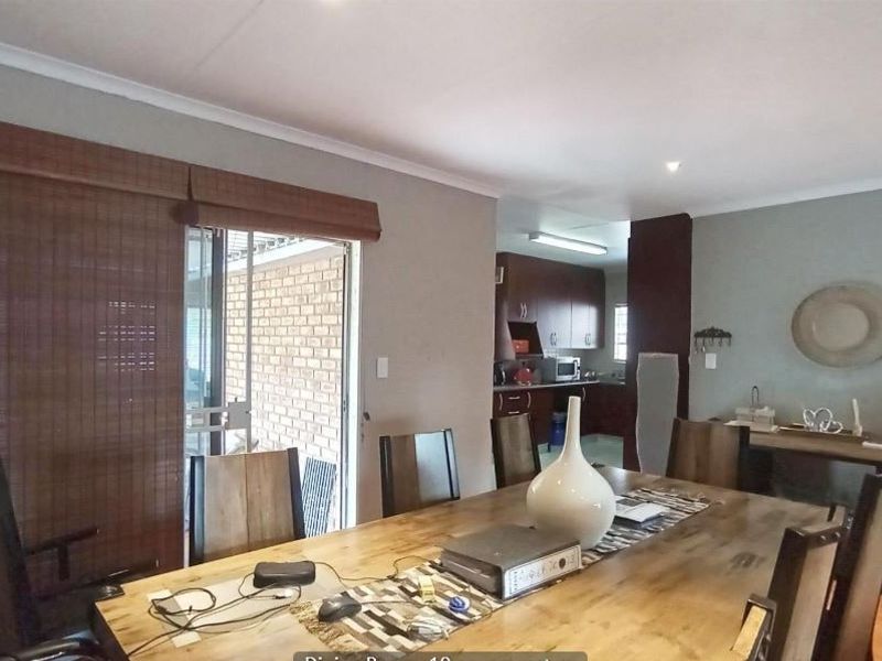 Open plan dining area featuring laminate flooring, recessed lighting, and a sliding glass door leading to an outdoor patio, with an adjacent kitchen.