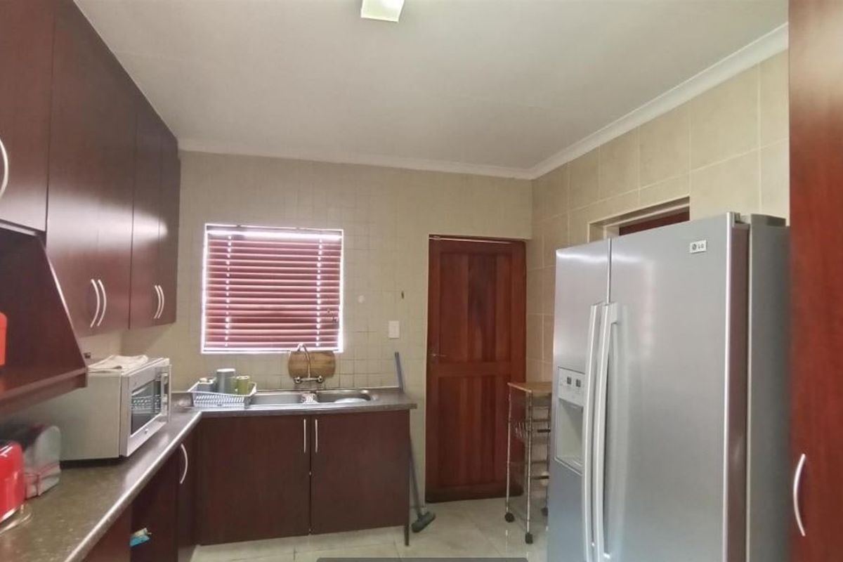 A functional kitchen featuring dark wood cabinetry, tiled backsplash, double sink, and tiled flooring, providing a practical workspace for daily meal preparation.