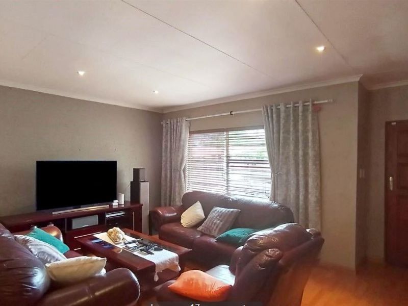 A comfortable living room featuring timber flooring, recessed downlighting, and a solid timber entrance door.