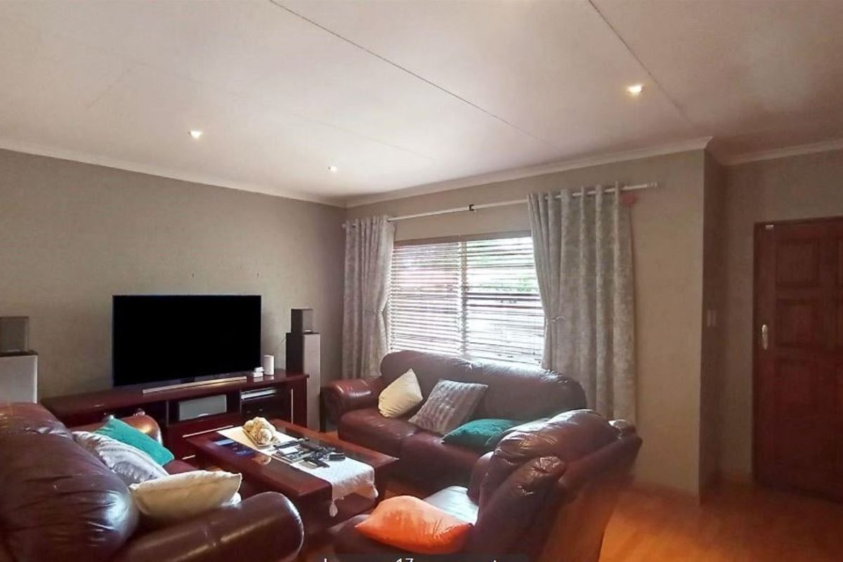 A comfortable living room featuring timber flooring, recessed downlighting, and a solid timber entrance door.