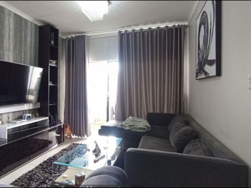 A comfortable living room featuring a built-in media shelving unit, neutral wall finishes, and a sliding glass door providing access to the outdoor area.