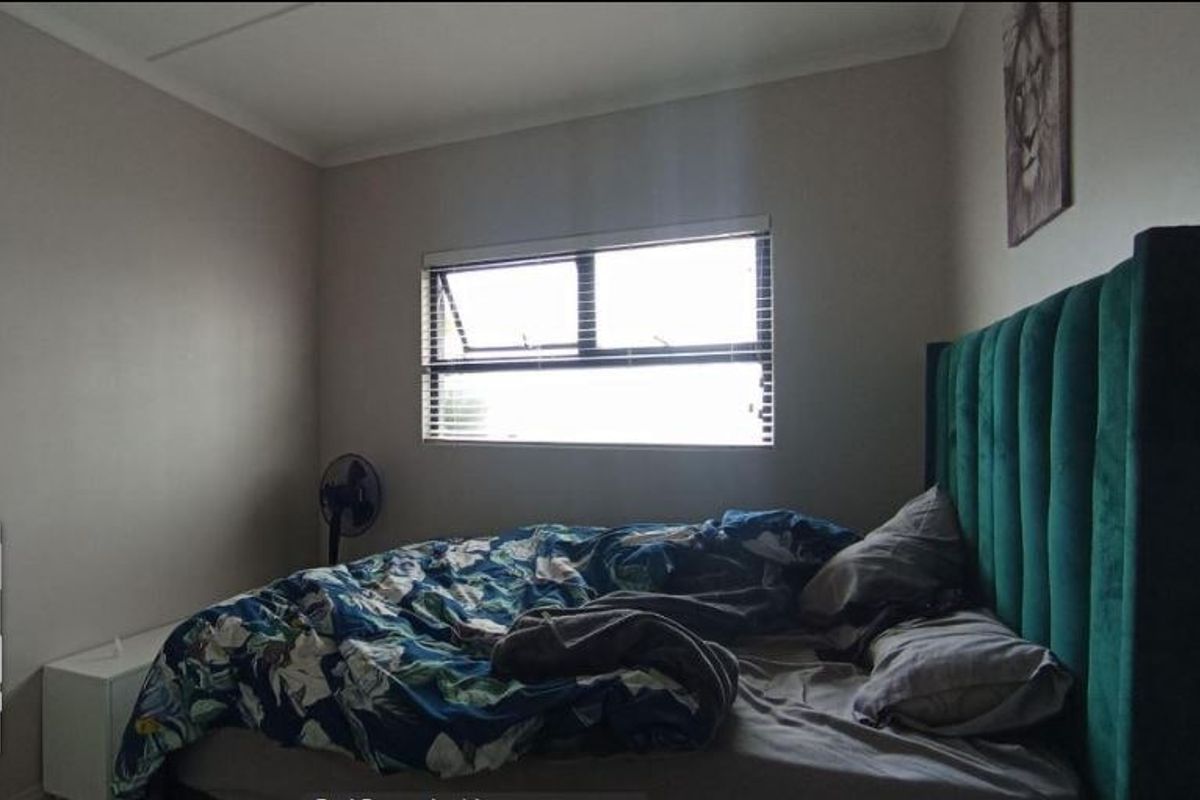 A bedroom featuring neutral wall finishes and a window with fitted venetian blinds.