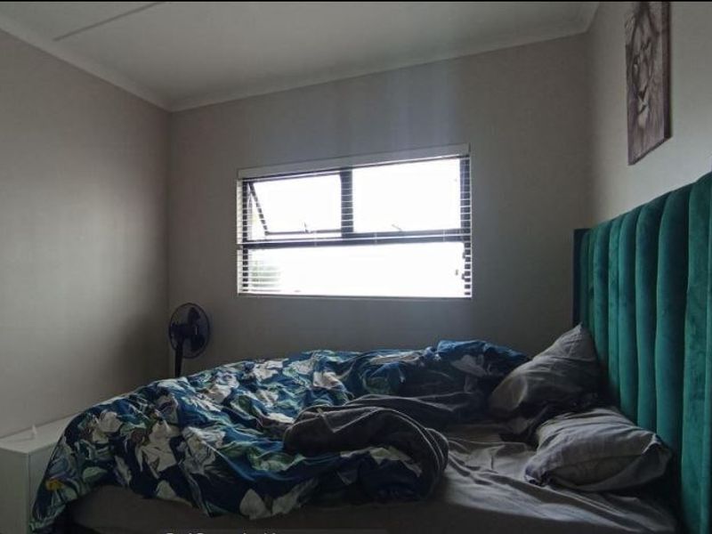 A bedroom featuring neutral wall finishes and a window with fitted venetian blinds.