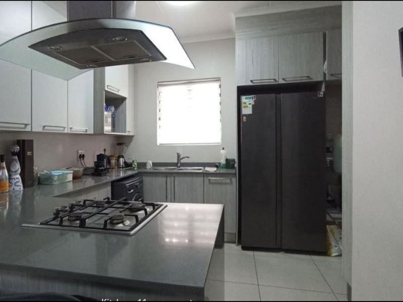 Modern kitchen featuring stone countertops, built-in cabinetry, a gas hob with extractor fan, and tiled flooring.