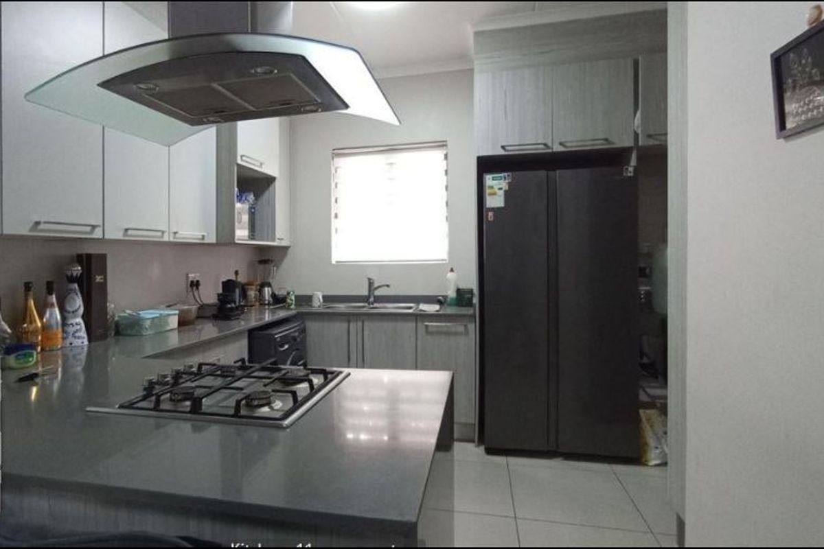 Modern kitchen featuring stone countertops, built-in cabinetry, a gas hob with extractor fan, and tiled flooring.