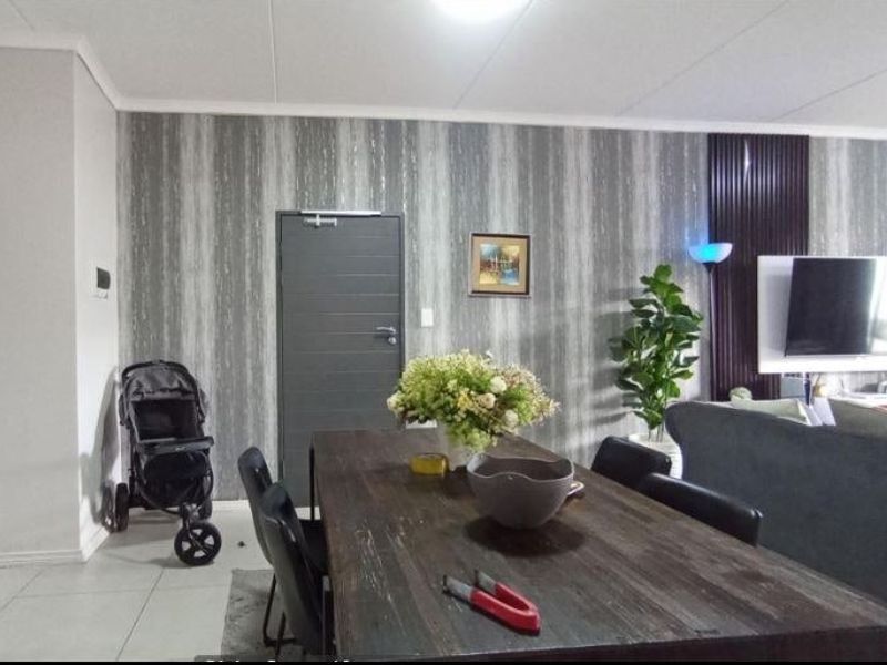 A living and dining area featuring tiled flooring, a decorative feature wall, and coved ceiling details.