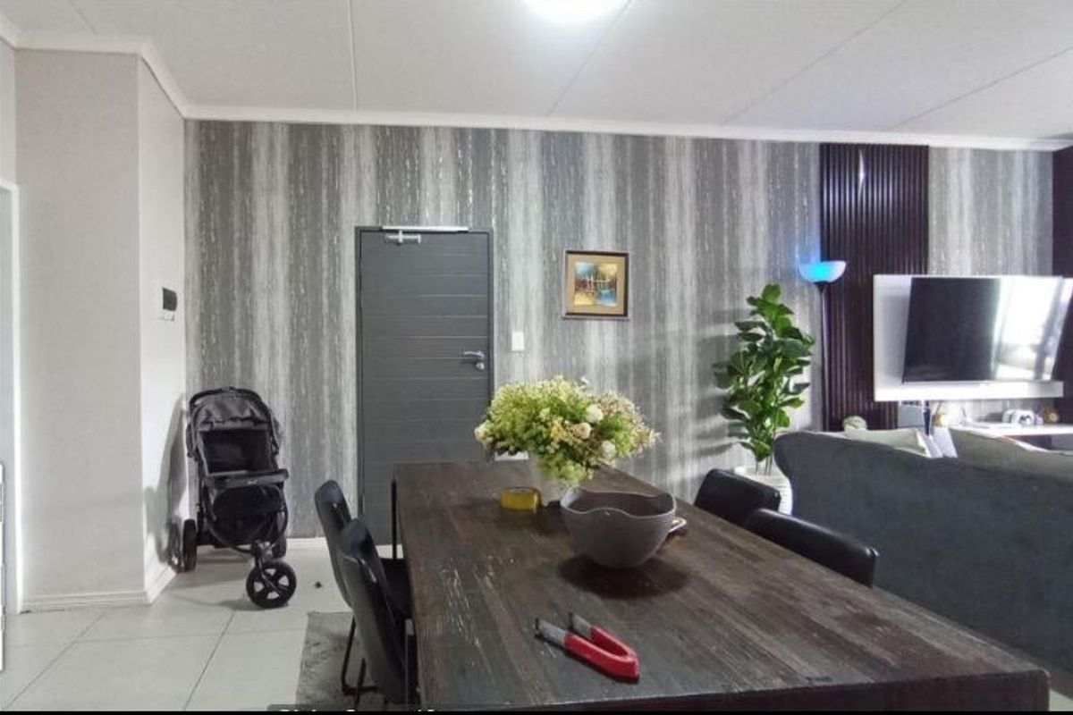 A living and dining area featuring tiled flooring, a decorative feature wall, and coved ceiling details.