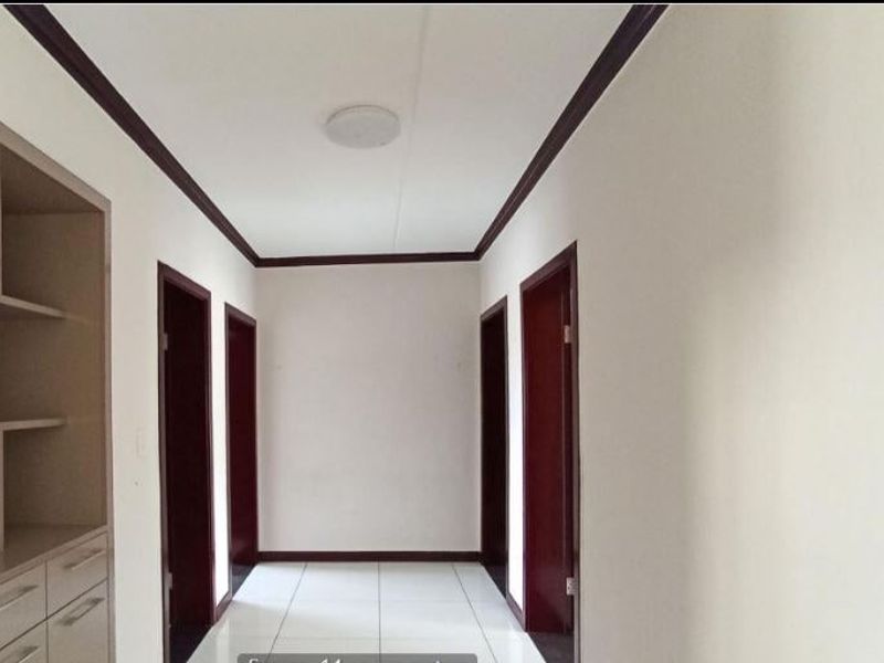 A clean, well-maintained hallway featuring tiled flooring, crown molding, and built-in cabinetry, providing access to multiple rooms.