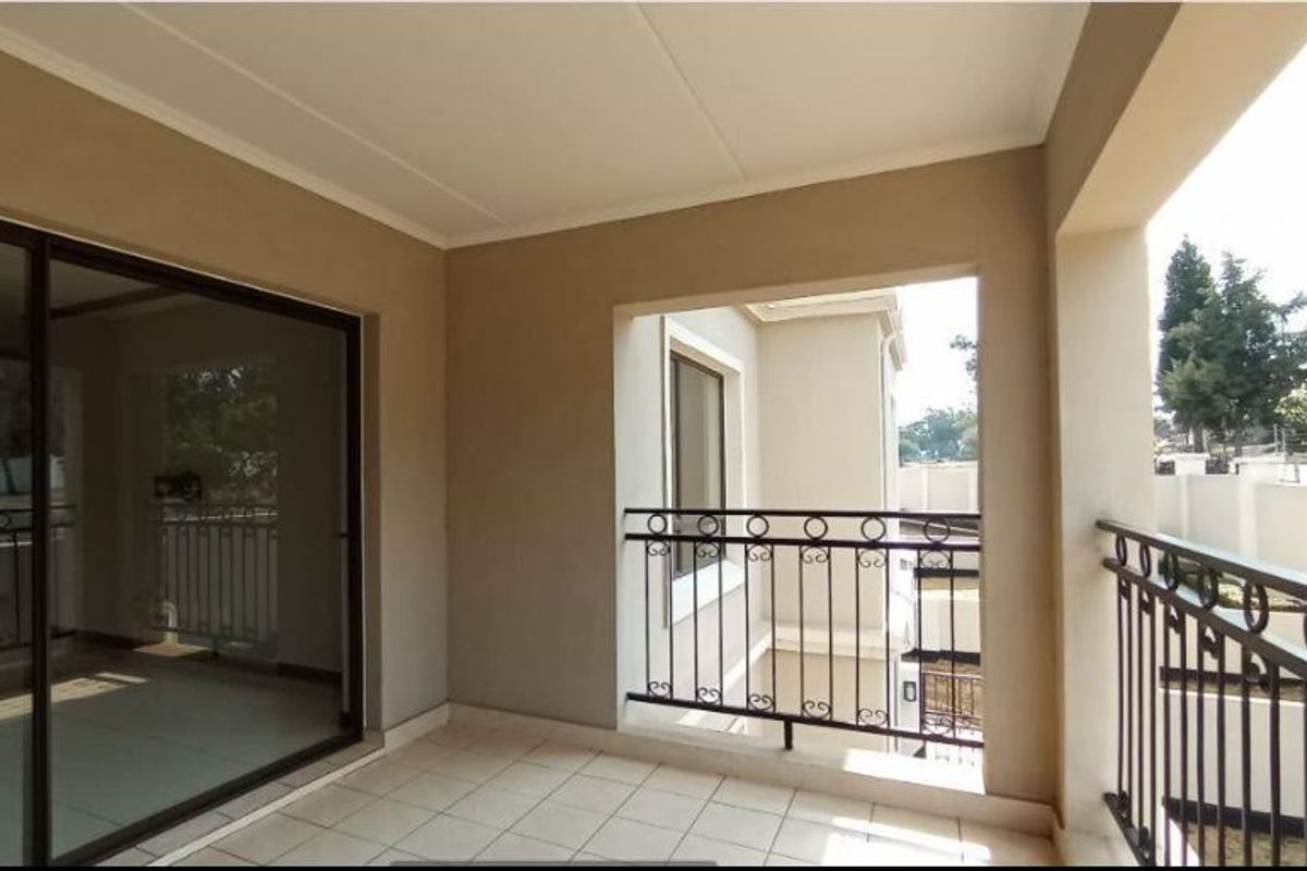 A covered balcony featuring tiled flooring and a wrought iron balustrade, accessible via a large sliding glass door.