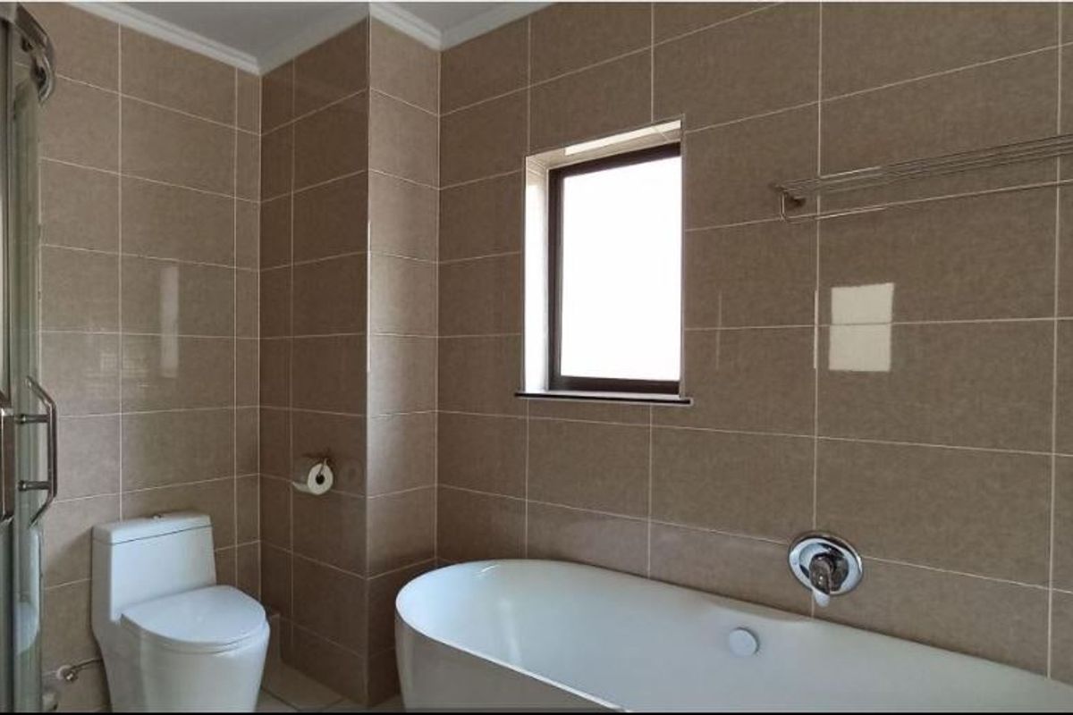 A clean, modern bathroom featuring a freestanding bathtub, a separate shower enclosure, and neutral wall tiling.