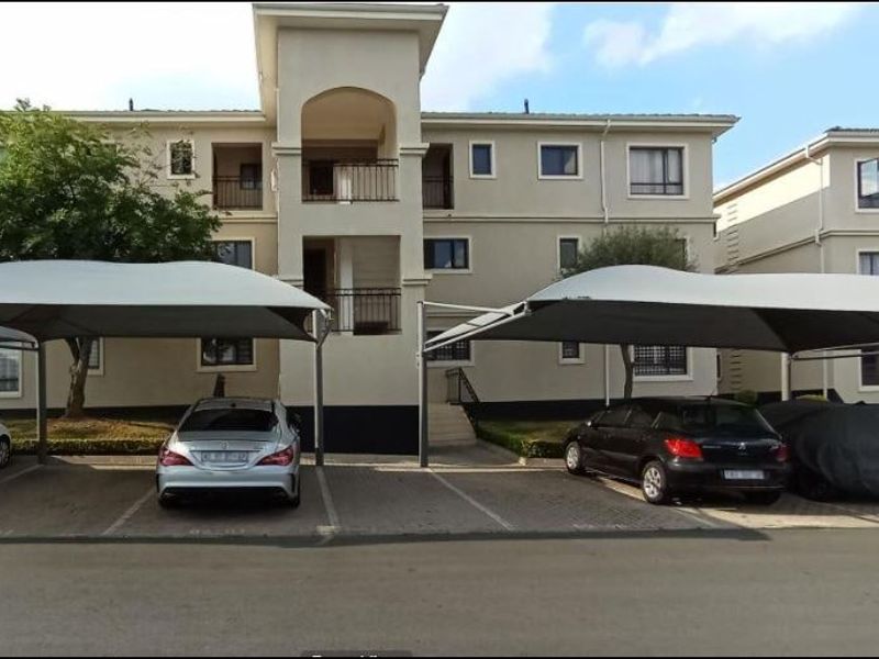 Front elevation of a multi-story apartment complex featuring covered parking bays and balconies.