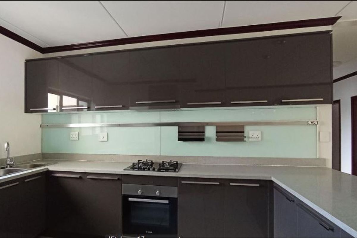 Modern kitchen featuring dark high-gloss cabinetry, stone countertops, a glass splashback, and integrated stainless steel appliances including a gas hob and oven.