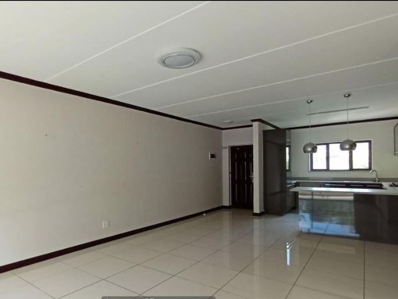 Spacious open-plan living and kitchen area featuring modern tiled flooring, sleek cabinetry, and a functional kitchen island with a built-in hob.